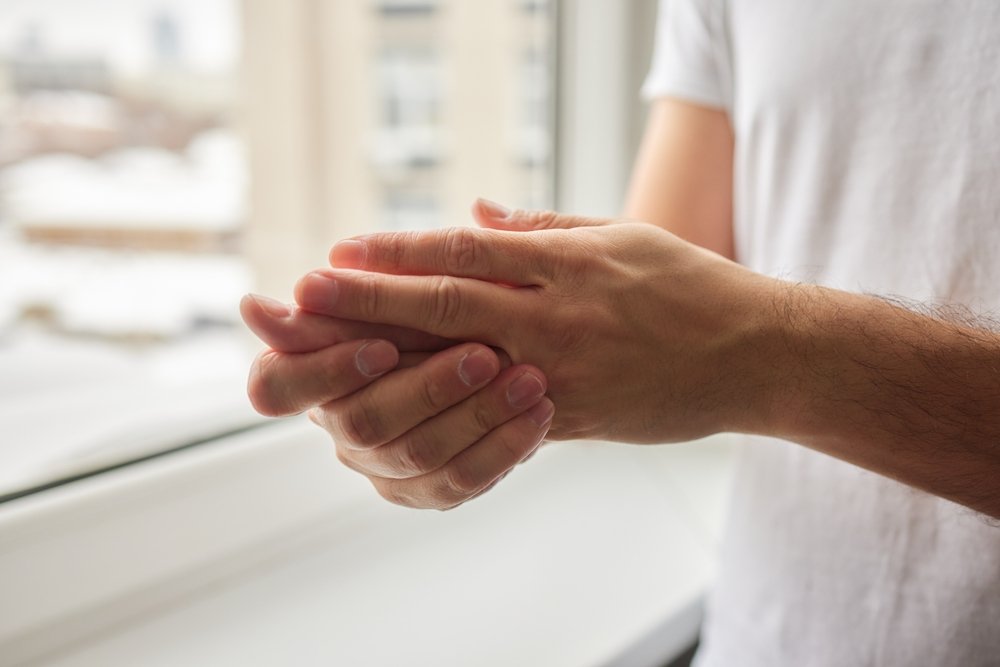 Man rubs cream into the eczema on his hands