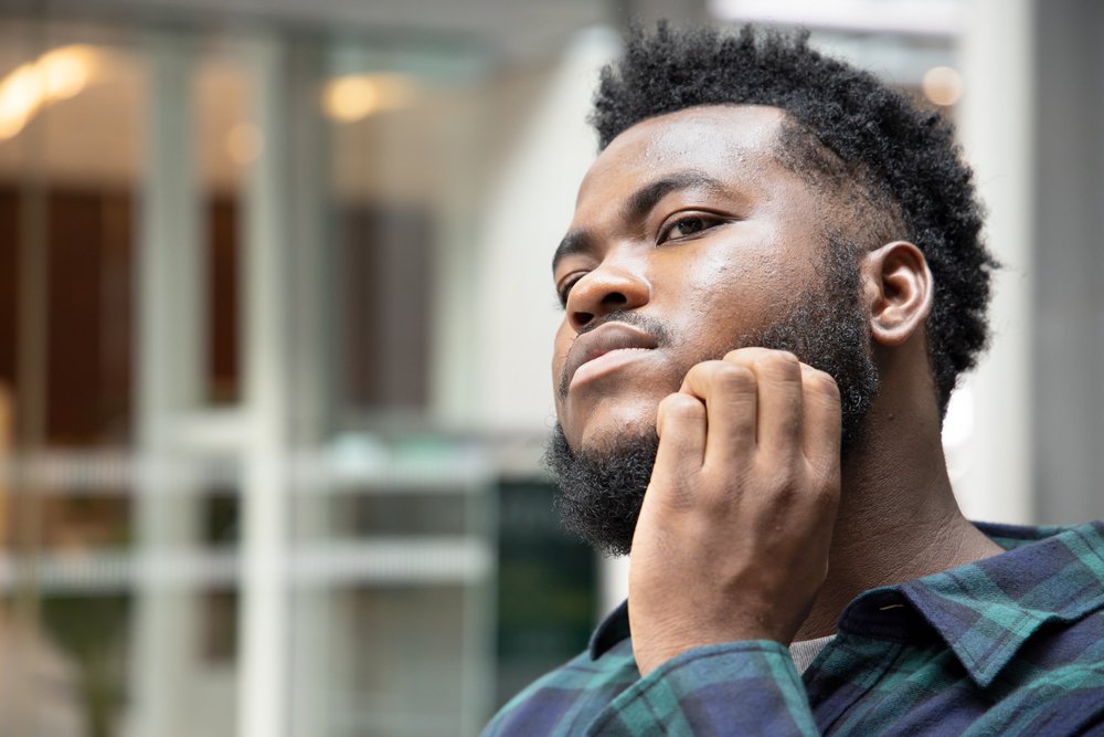 Afro-Caribbean man scratching the eczema on his face
