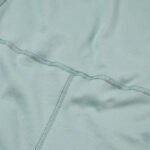 Close up of children's inseam-free seafoam dungarees. The close-up shows the seafoam colour, cotton fabric and external seam on the waist and crutch.