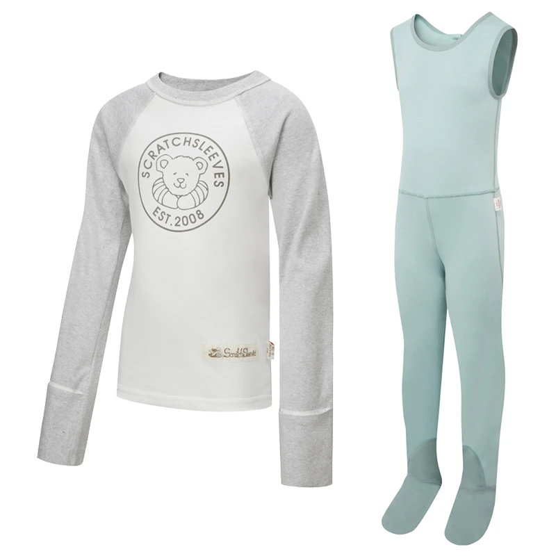 Front view of children's baseball style flip-mitt ScratchSleeves pyjama top with external shoulder, neck and hem seams. White body with grey screen printed logo featuring a bear and est.2008. Grey marl neck and sleeves, with mitts folded back. 100% cotton body and 100% natural silk mitts. External label and branding on the left side towards the base of the top. Front view of ScratchSleeves childrens seafoam dungarees with no inside leg seam and sewn in feet. Closed feet with a layer of grey, 100% woven cotton over the front of the foot and under the toe. Seafoam green, sleeveless body in 100% cotton jersey, edged in grey woven cotton trim on the arm and neck.