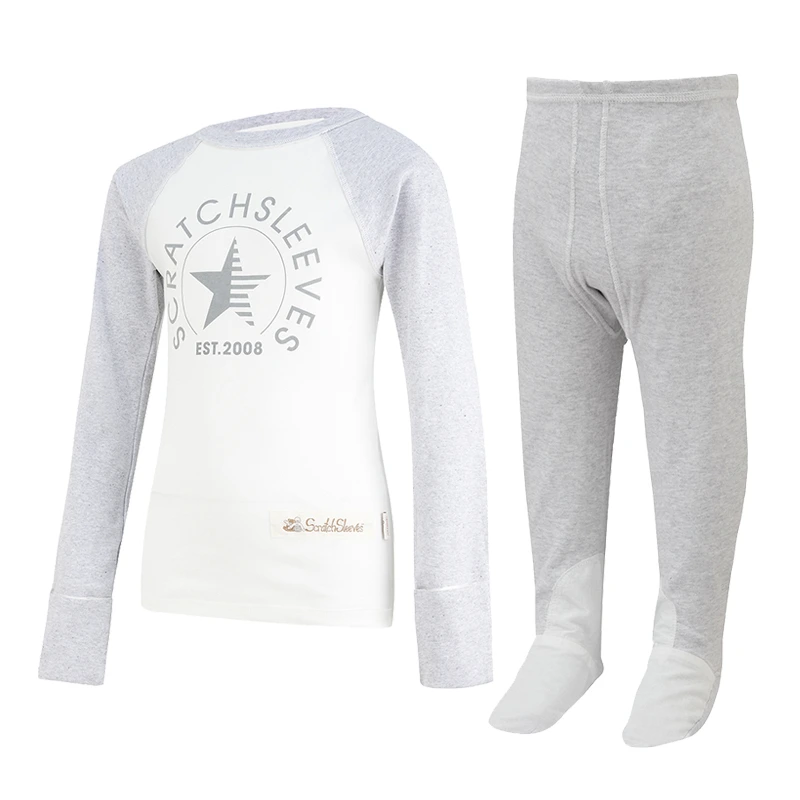 Front view of children's baseball style flip-mitt ScratchSleeves pyjama top with external shoulder, neck and hem seams. White body with grey screen printed logo featuring a bear and est.2008. Grey marl neck and sleeves, with mitts folded back. 100% cotton body and 100% natural silk mitts. External label and branding on the left side towards the base of the top. Front view of ScratchSleeves childrens seafoam dungarees with no inside leg seam and sewn in feet. Closed feet with a layer of grey, 100% woven cotton over the front of the foot and under the toe. Seafoam green, sleeveless body in 100% cotton jersey, edged in grey woven cotton trim on the arm and neck.